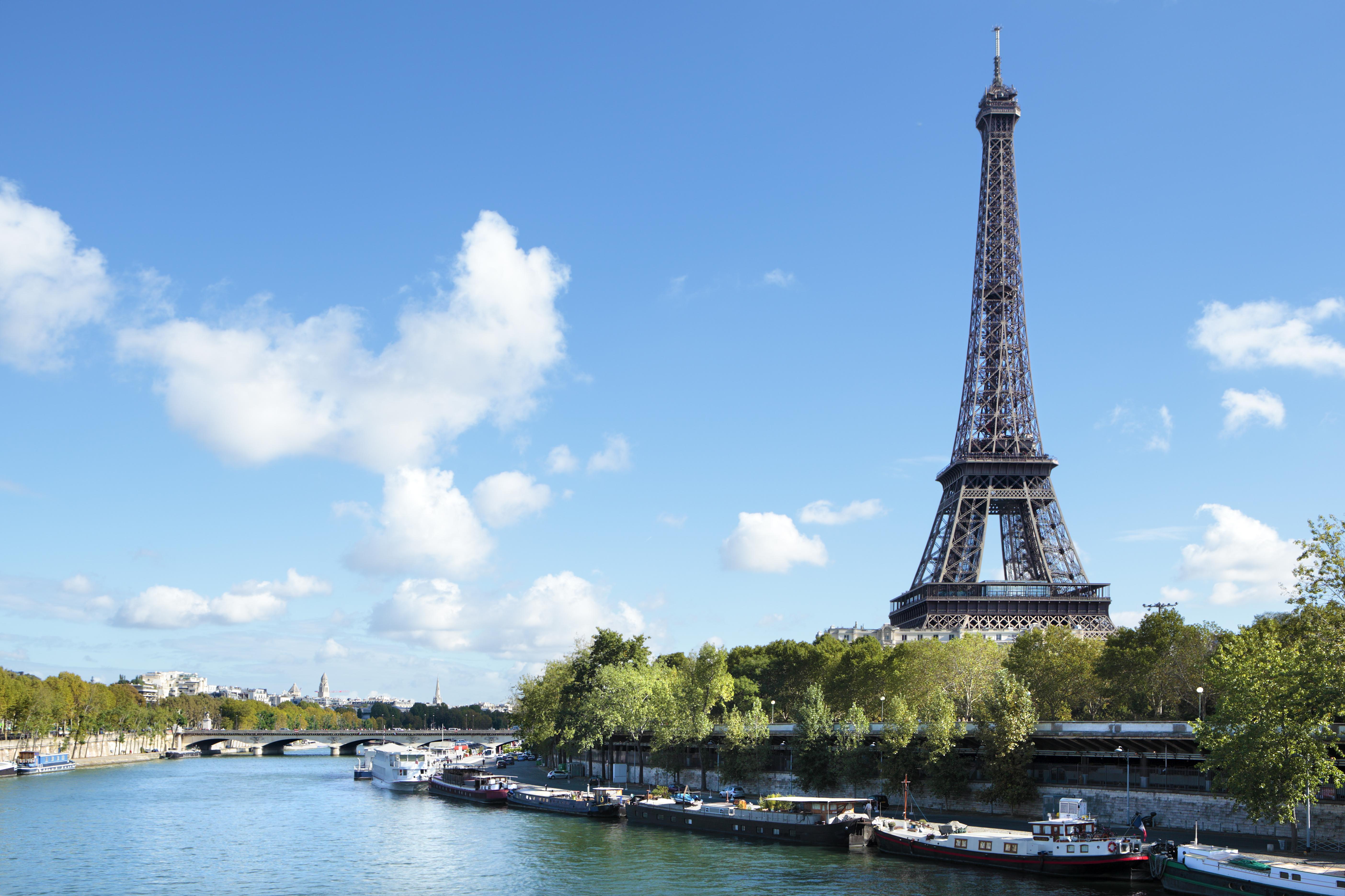 Eiffel Tower landscape taken from the south side, with River Seine, boats and blue sky with copyspace..